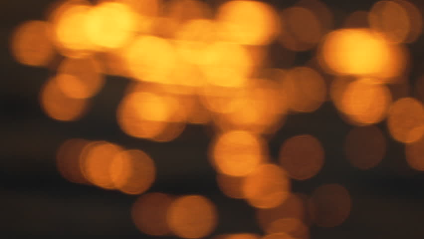 blurry yellowish-orange sunset over water. The water appears to be rippling and the sky is filled with a warm, golden glow.