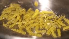 Yellow Italian fusilli pasta falling into hot water in slow motion. - Powered by Shutterstock - Get 15% off with code: PIKWIZARD15