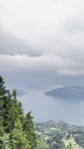 Panoramic view of Lake Lucerne from the Rigi viewpoint as heavy clouds and approaching fog roll over the landscape, partially hiding the mountains and water.