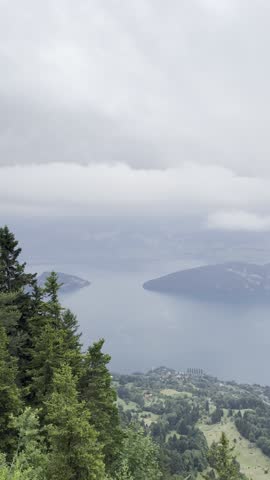 Panoramic view of Lake Lucerne from the Rigi viewpoint as heavy clouds and approaching fog roll over the landscape, partially hiding the mountains and water.