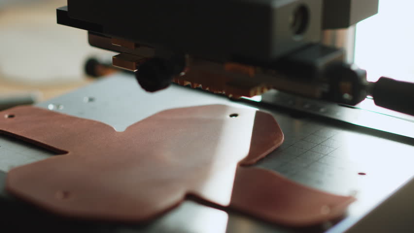 Leather embossing on hot stamping machine close up branding text pressed into brown hide for handmade wallet or case production