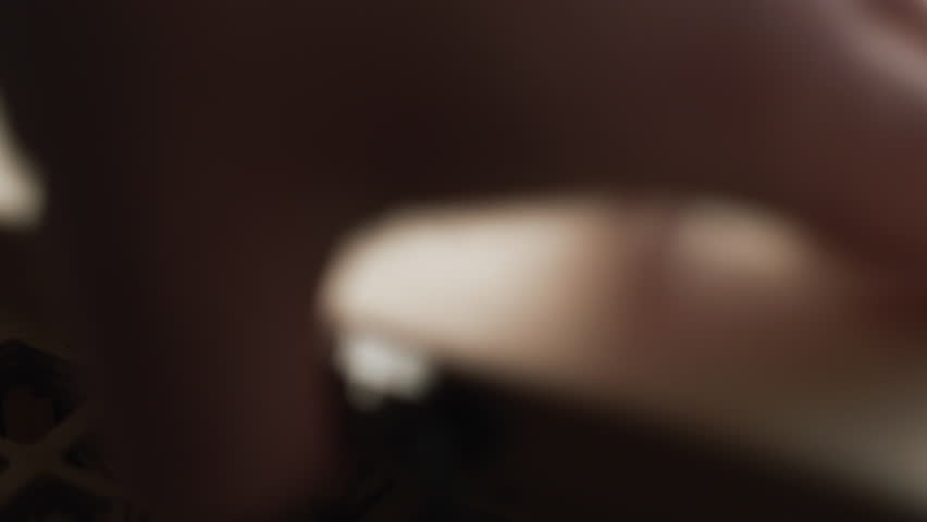 Brass alphabet letters in wooden tray picked with tweezers for hot stamping monograms and logos in artisan studio close up