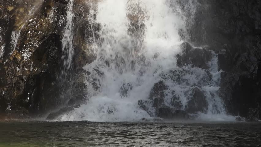 Waterfall is bathed in sunlight, creating a rainbow in the afternoon.