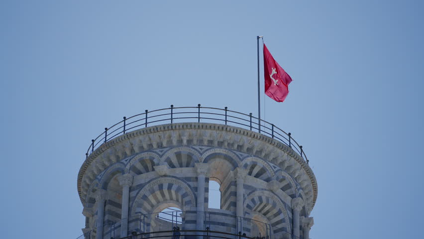 Leaning Tower of Pisa with red waving flag in sunny background