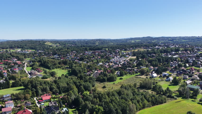 Aerial view shows a town surrounded by trees and hills on a sunny day. Skawina, Malopolska Poland