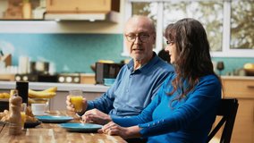 Senior couple enjoys a cozy morning routine with breakfast together. Husband and wife shares candid moment and laughing at the kitchen counter, serving healthy food over warm coffee. Camera A. - Powered by Shutterstock - Get 15% off with code: PIKWIZARD15