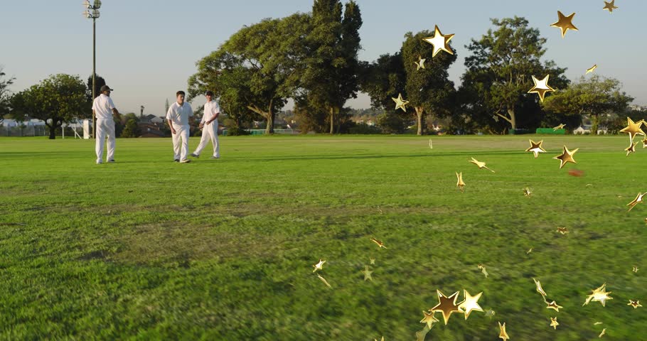 Three cricket players stooping picking red ball running bowling training under gold stars by them. Teammates, outdoor, field, grass, sunlit, motion, glow