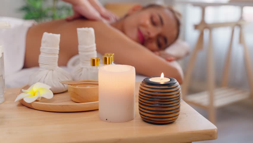 Beautiful woman in bathrobe getting back massage treatment at beauty spa. Attractive young girl lying down on massage bed getting relaxing physiotherapy service from masseuse for body in spa clinic.
