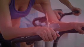 Fitness partners pedaling on bikes while camera pulling back, ECG pulsing to monitor heart rate. Cycling, cardio, duo, gym, studio, momentum, focused - Powered by Shutterstock - Get 15% off with code: PIKWIZARD15