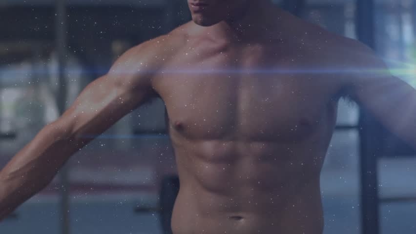 Fitness model rotating torso, holding pose in gym, camera shift overlaying flares and dust for ad. Athletic, muscular, rotation, stance, flare, particles, studio