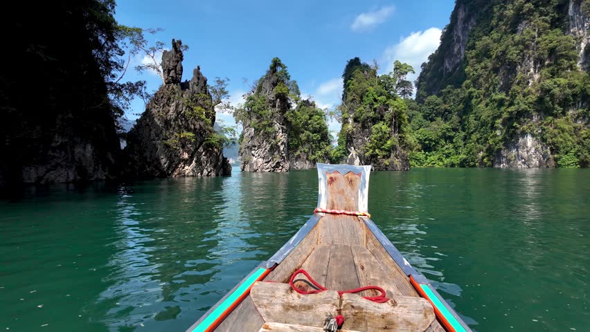 Glide through the tranquil waters of Khao Sok National Park aboard a traditional longtail boat, surrounded by stunning limestone formations and lush greenery. Experience natures beauty in Thailand.