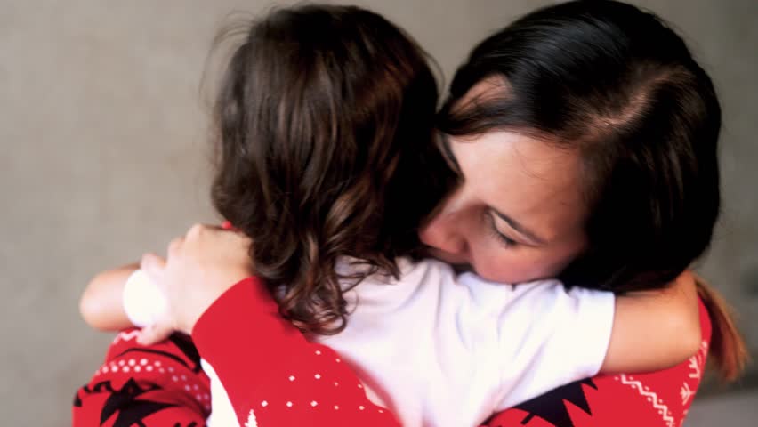 Latin mother hugging her toddler daughter during Christmas season. Family love