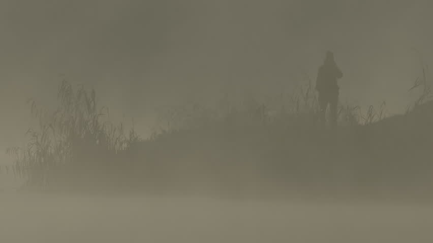 Fog early in the morning on the Adda River with a peninsula on the horizon and the silhouette of a person.