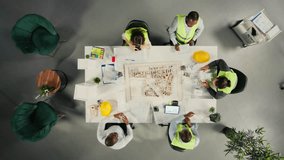 Architectural team in office plans urban infrastructure with artificial intelligence tools, HUD icons symbolize digital ecosystem. Aerial view of civil engineers designing buildings with AI assistance - Powered by Shutterstock - Get 15% off with code: PIKWIZARD15