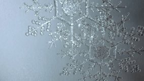 Glittering clear plastic snowflake ornament swaying gently, set against a textured gray background, creating a serene winter and Christmas ambience perfect for holiday footage - Powered by Shutterstock - Get 15% off with code: PIKWIZARD15
