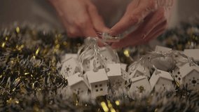 Hands turning on battery-powered string lights shaped like small white houses with snowflake cutouts, creating cozy glow for festive holiday decorations, close-up. Concept of home festive mood. - Powered by Shutterstock - Get 15% off with code: PIKWIZARD15