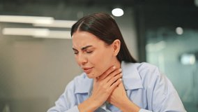 Feeling unwell, young woman suffers from a painful sore throat and persistent coughing at office desk. Depicts discomfort, illness, and health concerns, showing difficult moment. - Powered by Shutterstock - Get 15% off with code: PIKWIZARD15