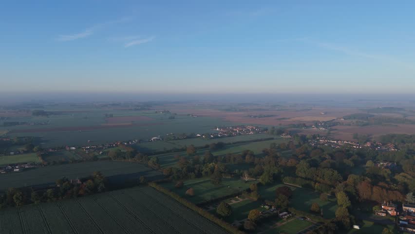 Rural aerial scene of open countryside farmland dawn or sunset blue tones. Misty uk morning in isolated landscape fresh winter autumn frosty sunrise, sunset, trees and farmhouse, green pastures