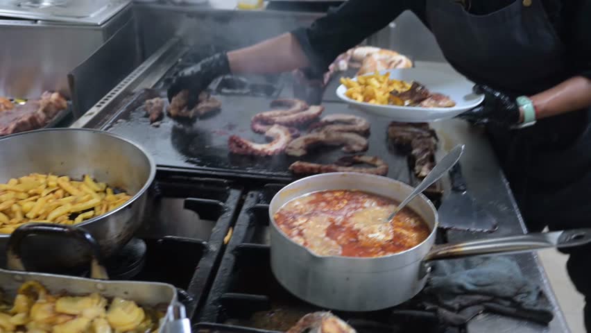 Professional chef grilling meat and calamari on a plancha
