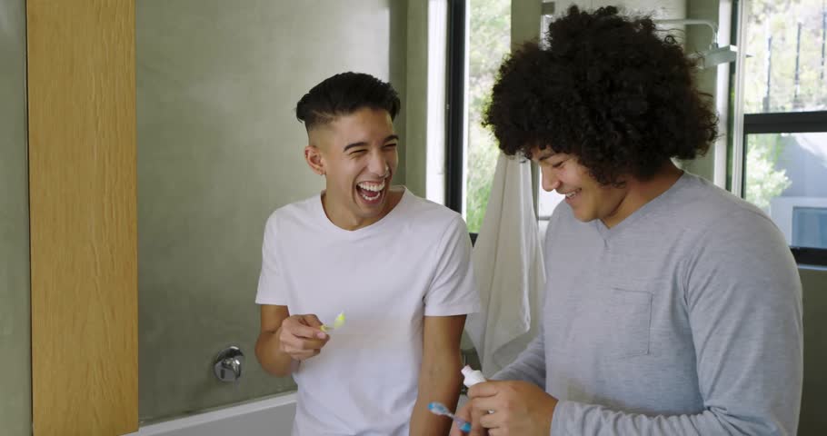 Two men at sink, dispensing toothpaste and brushing teeth for health, metallic hearts over hands. Toothbrush, brush, dentalcare, hygiene, bathroom, mirror, friendship