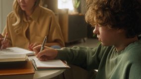 Side view shot of curly haired teenage boy writing in notebook while studying at home with little sister drawing in background, soft aesthetic, copy space - Powered by Shutterstock - Get 15% off with code: PIKWIZARD15