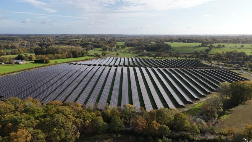 Aerial drone view of solar panel fields in the Kent countryside, showcasing clean renewable energy generation and the growing shift toward sustainable power in the United Kingdom.