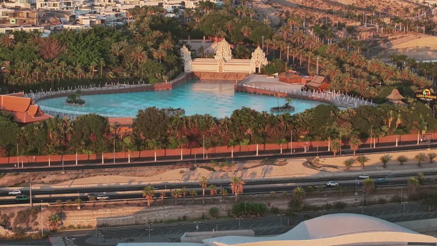 Aerial view of Siam Park in Tenerife at sunset, showing pools, palms and the city backdrop.