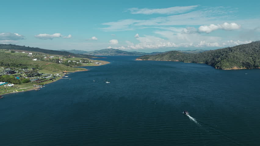 Spectacular aerial footage of Lago Calima in Valle del Cauca, Colombia. Captivating landscape with pristine water and surrounding lush hills under a clear blue sky. Perfect for drone video lovers.