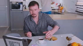 caucasian man enjoys morning meal, casual morning scene featuring man and partner at kitchen table, relaxed caucasian man and partner sharing breakfast amidst kitchen setting with coffee and tablet - Powered by Shutterstock - Get 15% off with code: PIKWIZARD15