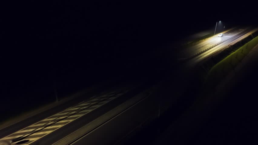 Sedan cruising in darkness, headlights guiding through street. Car driving on road at night, headlights lighting way. Vehicle moving through dark street, beams illuminating path. Auto traveling along