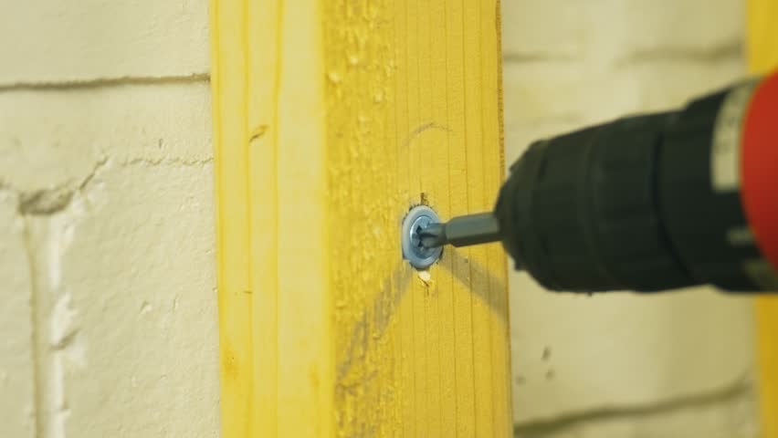 Screwing fastener into wooden surface using drill with clutch slipping and tool jerking. Driving screw into timber board using power driver with ratchet clicking and bit jumping. Inserting hardware