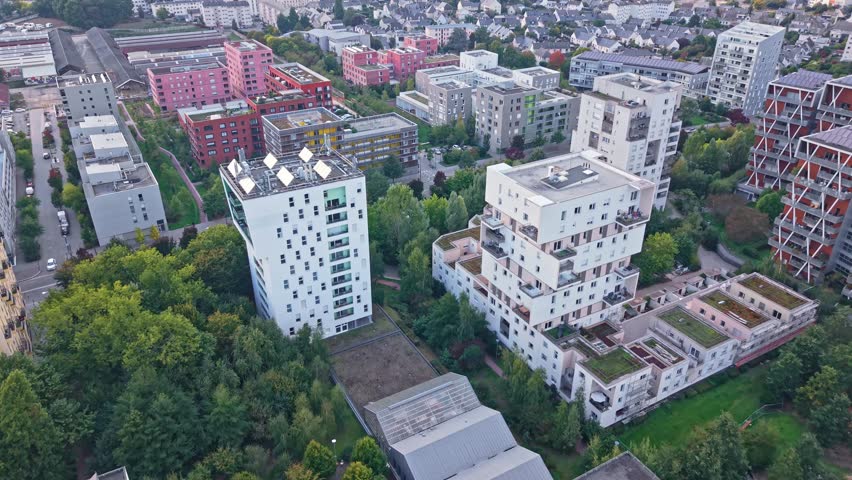 High-angle overview of the distinctive La Courrouze urban renewal district, showcasing modern, angular residential towers interspersed with large patches of natural green parkland and foliage.