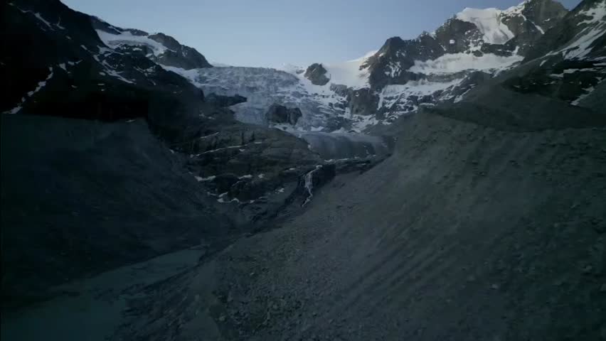 Drone sunrise advance toward a waterfall and glacier meltwater streams near Moiry Glacier in Valais, Switzerland, in the Swiss Alps.