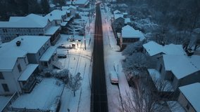 Snow-covered American street in early winter morning light, houses lined along quiet residential road, soft streetlamp glow reflecting on fresh snow in peaceful small town. Aerial Birds Eye flight. - Powered by Shutterstock - Get 15% off with code: PIKWIZARD15
