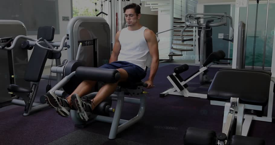 Man performing controlled leg extensions in gym, gripping handles and initiating reps for strength. Quadriceps, machine, resistance, seated, repetition, fitness, daylight