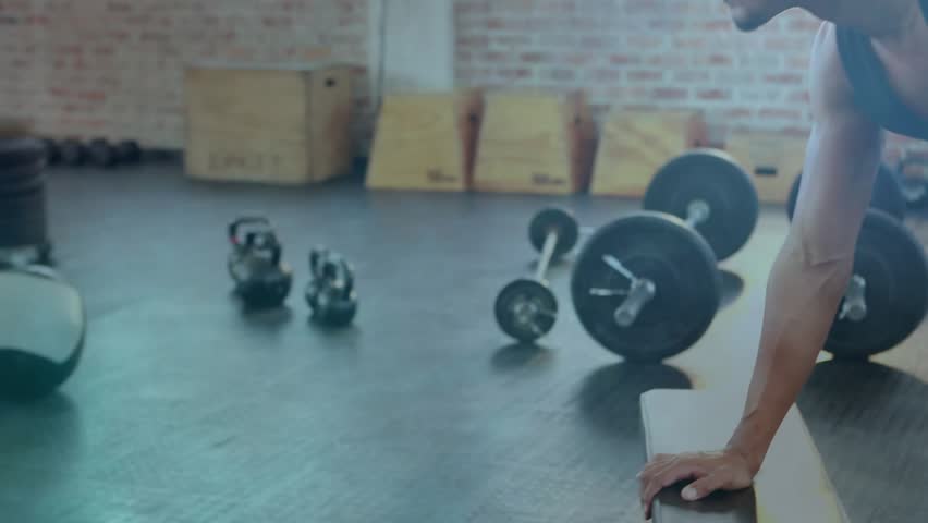 Man entering frame grabbing dumbbell, doing single arm rows for fitness with golden overlay. Gym, athlete, weights, kettlebell, core, focus, posture
