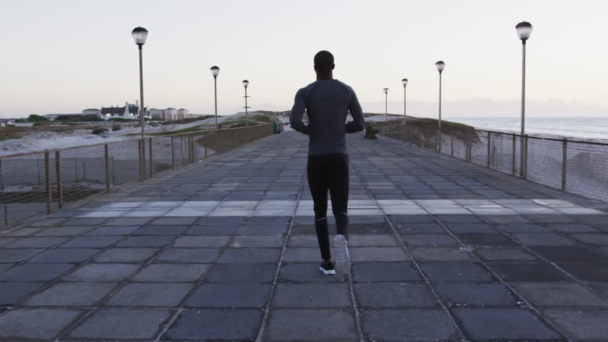 Man jogging coast while pink LEVEL UP graphic appearing causing 3D title over runner aiding fitness. Athlete, seaside, boardwalk, outdoor, motivation, momentum, horizon