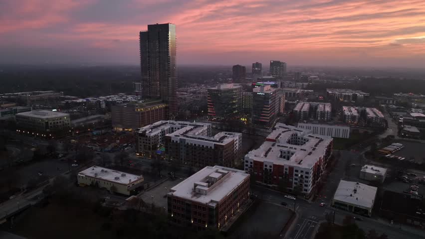Aerial view of Charlotte, North Carolina at sunset, showing modern high rises, mixed use developments, residential blocks and city’s expanding urban skyline in warm evening light. Wide shot.