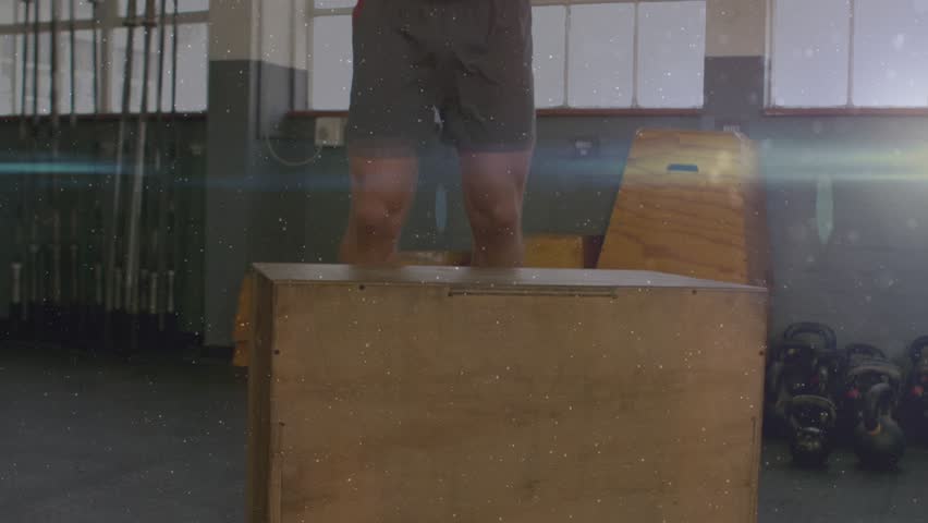 Male athlete initiating jump in gym for fitness under windows, jumping onto plyo box landing squat. Sportsman, workout, platform, wooden, kettlebell, focus, dynamic