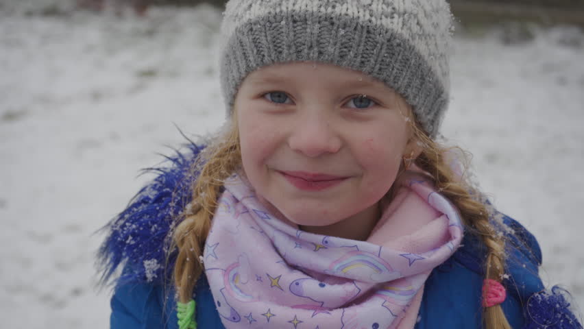 close-up of a little girl on a snowy background, smiling little girl in winter when snow falls