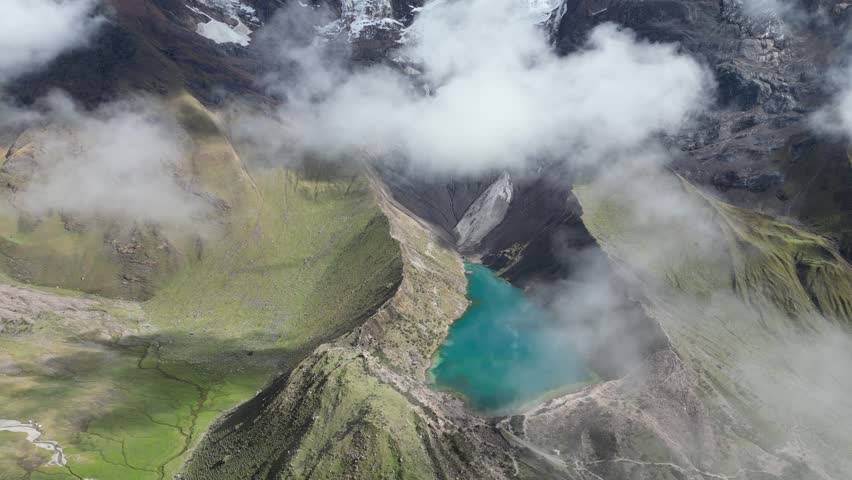 Aerial shot of Humantay Lake in the Andes, Peru, intense cloud reflections shimmering on sunlit turquoise water.