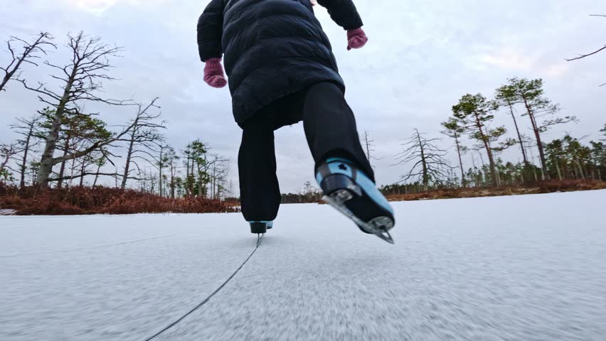 Real Time Low Angle Shot of Ice Skating Woman Across Frozen Swamp Lake