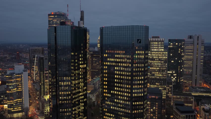 Aerial ascending footage showing illuminated skyscrapers of the Frankfurt financial district. Modern office buildings forming a beautiful night skyline