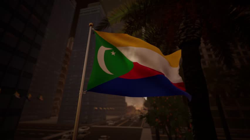Comoros is depicted here during the serene golden hour, where the warm glow of the setting sun bathes the national banner in rich, amber tones. The backdrop features the shimmering waters of the Indian Ocean, hinting at the coastal geography of the islands. As the light fades, the yellow and red stripes of the standard take on a deep, saturated hue, while the green chevron maintains a dark, dignified contrast. The white crescent and stars catch the last rays of daylight, creating a striking focal point against the twilight sky. The air is calm, causing the textile to sway lazily rather than snap, suggesting the peaceful end of a day in the tropics. This visual is excellent for emotive storytelling, tourism campaigns promoting the beauty of the archipelago, or introspective segments in documentaries. The fabric reveals its texture in the grazing light, showing the quality of the material. In the distance, the faint outline of Mount Karthala can be imagined, adding depth to the scene. The motion is fluid and hypnotic, capturing the relaxed atmosphere of the region at dusk. This sequence serves well for content related to national holidays, reflecting on the history and future of the Union. The interplay of shadow and light creates a cinematic aesthetic suitable for high-end production needs, emphasizing the natural beauty surrounding the emblem.