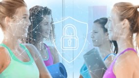 Preparing for fitness, two women with blue-gray mats shifting, smiling under digital shield padlock. Yoga, studio, mirror, network, camaraderie, motivation, bright - Powered by Shutterstock - Get 15% off with code: PIKWIZARD15