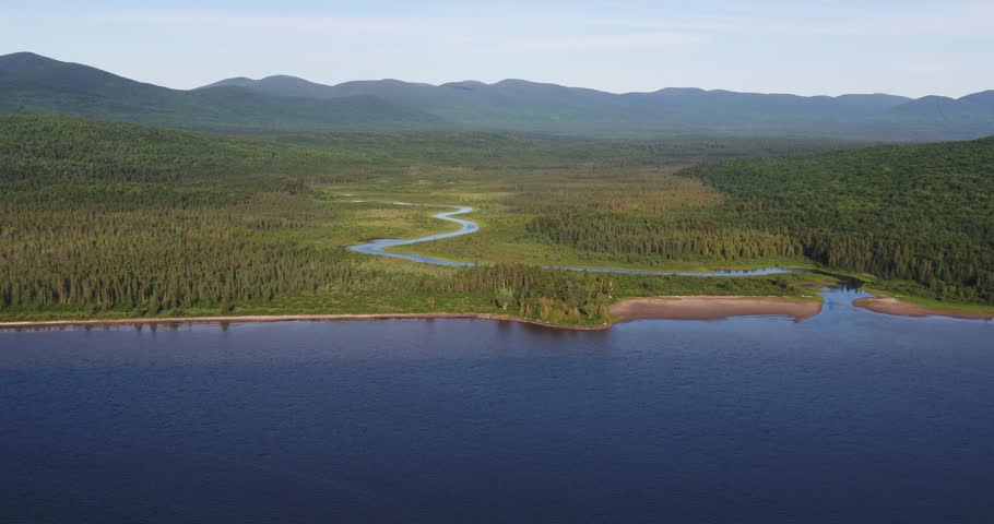 Aerial view of a sinuous river leading toward Lac aux Araignees with a mountain range beyond. Scenic summer wilderness landscape in Frontenac Quebec and the Eastern Townships.