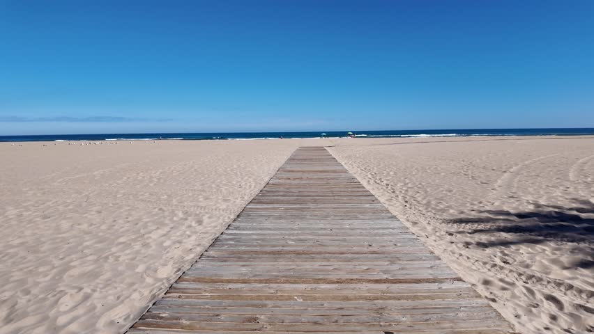 Gandia sign advertising the spanish city on a sandy beach with a clear blue sky