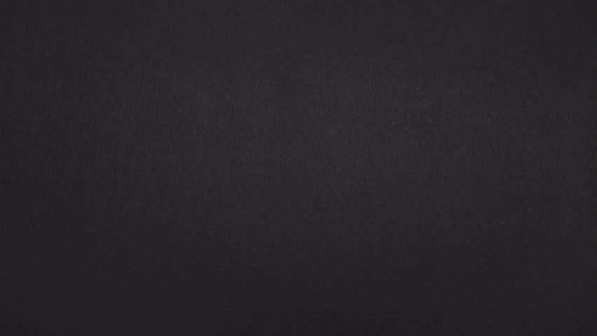 Real black paper rips vertically and slides sideways, revealing footage with a clean paper transition.
