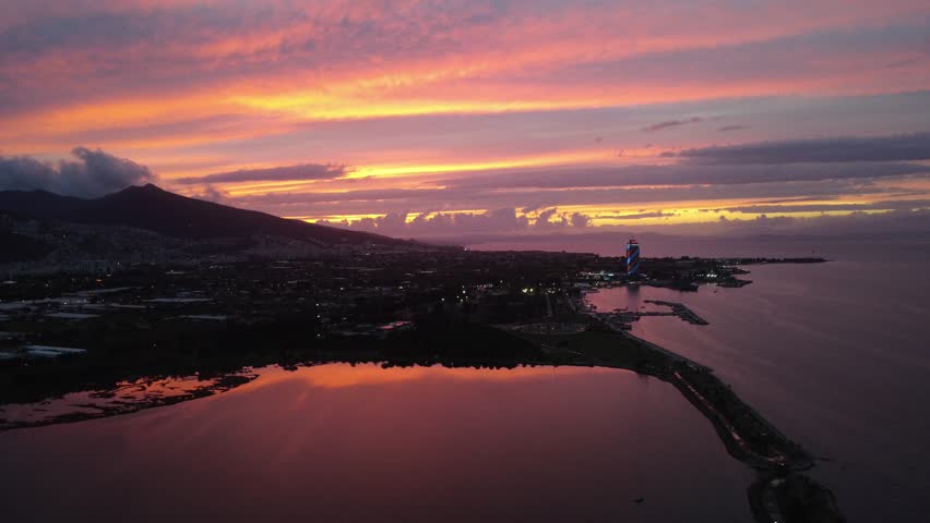 A serene aerial view captures the warm colors of sunset reflecting over a quiet pond surrounded by natural landscape.