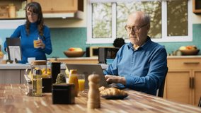 Elderly couple cheering with a jolly smile after hearing good news, sitting at kitchen table during morning routine. Aged husband and wife celebrate proud achievement in retired life. Camera B. - Powered by Shutterstock - Get 15% off with code: PIKWIZARD15